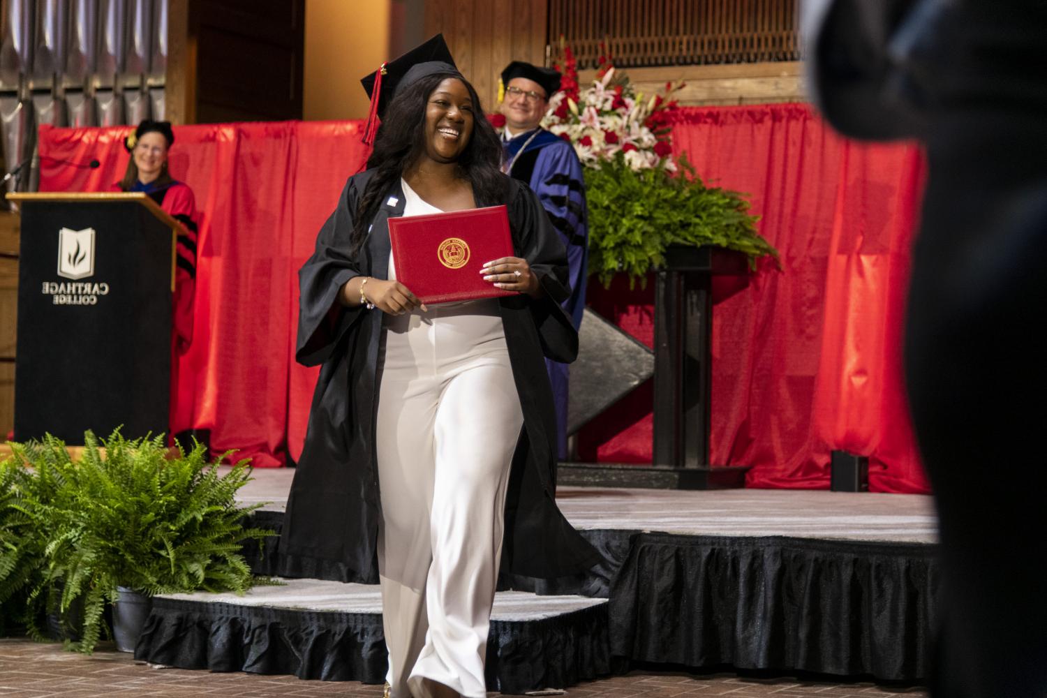 A 2023 <a href='http://qkcg.syudia.com'>BETVLCTOR伟德登录</a> graduate beams as she leaves the Commencement stage after receiving her diploma from Carthage President John 吞下.